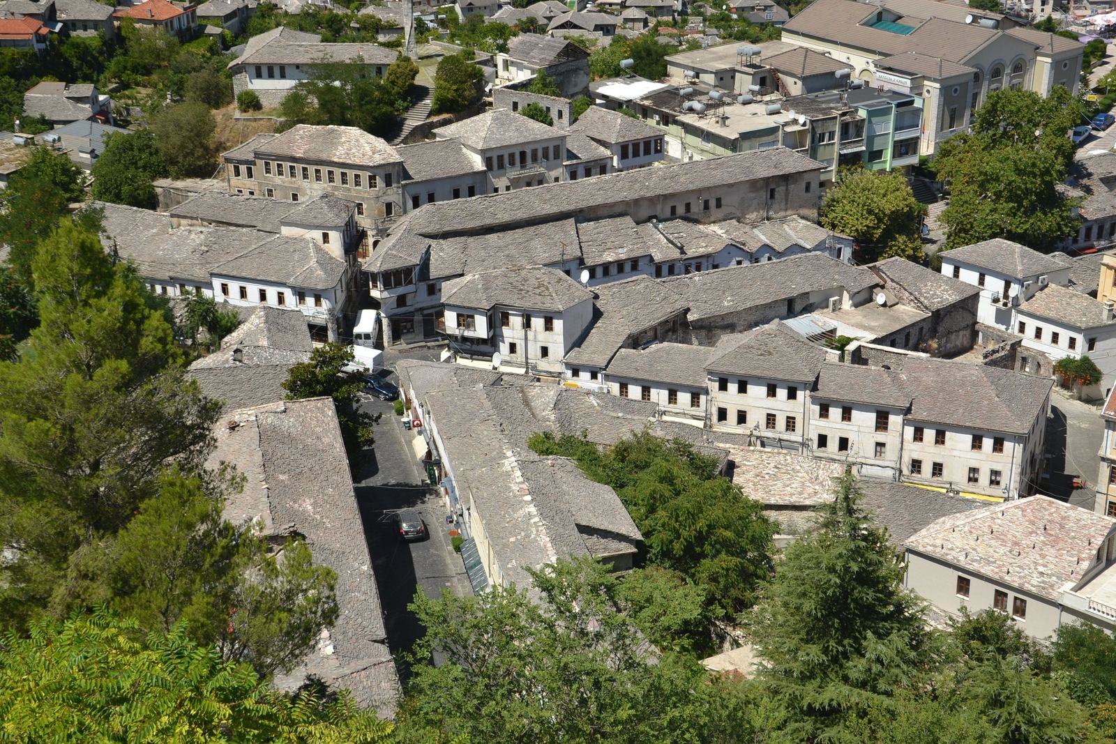 Houses with grey stone roofs among the greenery of Gjirokastër, seen from above