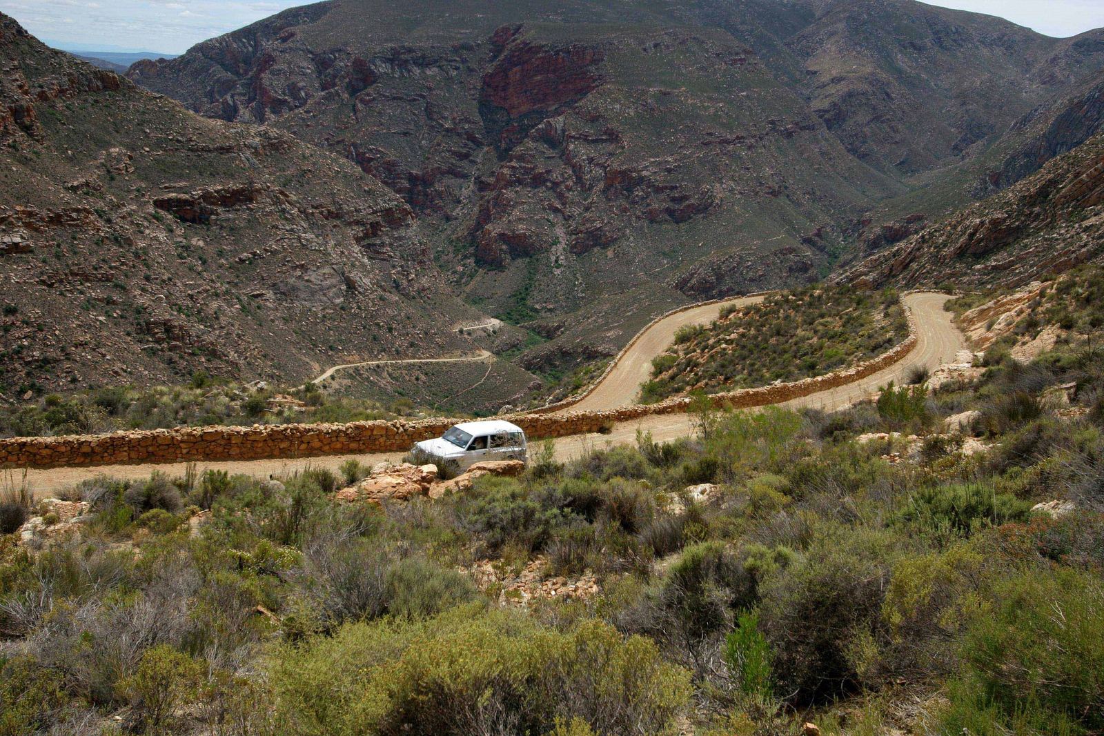 Gravel road with dry-stone walls zigzagging through the rocky gorge of the Swartberg Pass