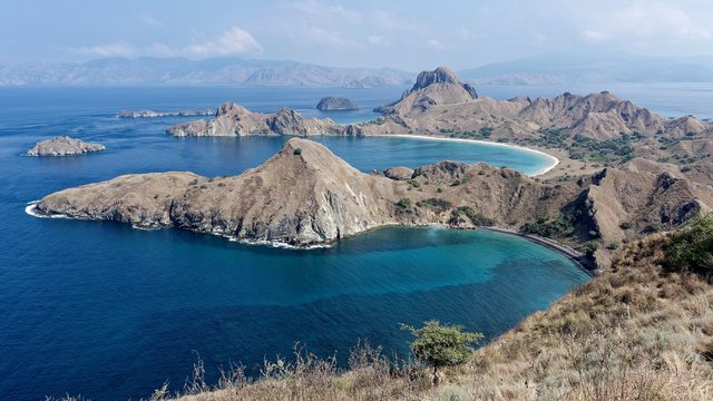View from the top of Padar Island over three bays with turquoise water and dry hills in Komodo National Park