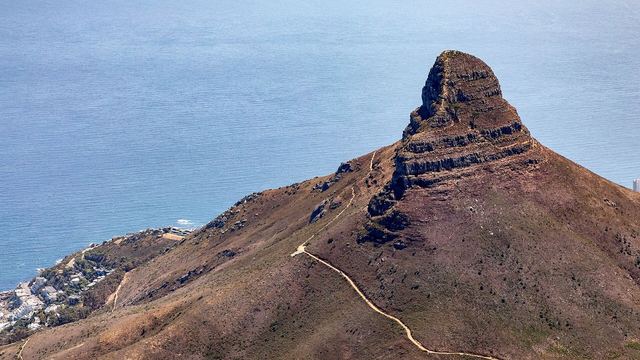 De top van Lion's Head gezien vanaf de Tafelberg, met Kaapstad en de kust