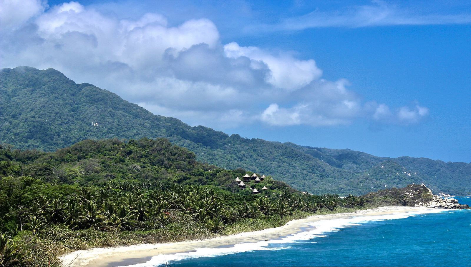 Strand en jungle in het Tayrona nationaal park gezien vanaf een uitkijkpunt