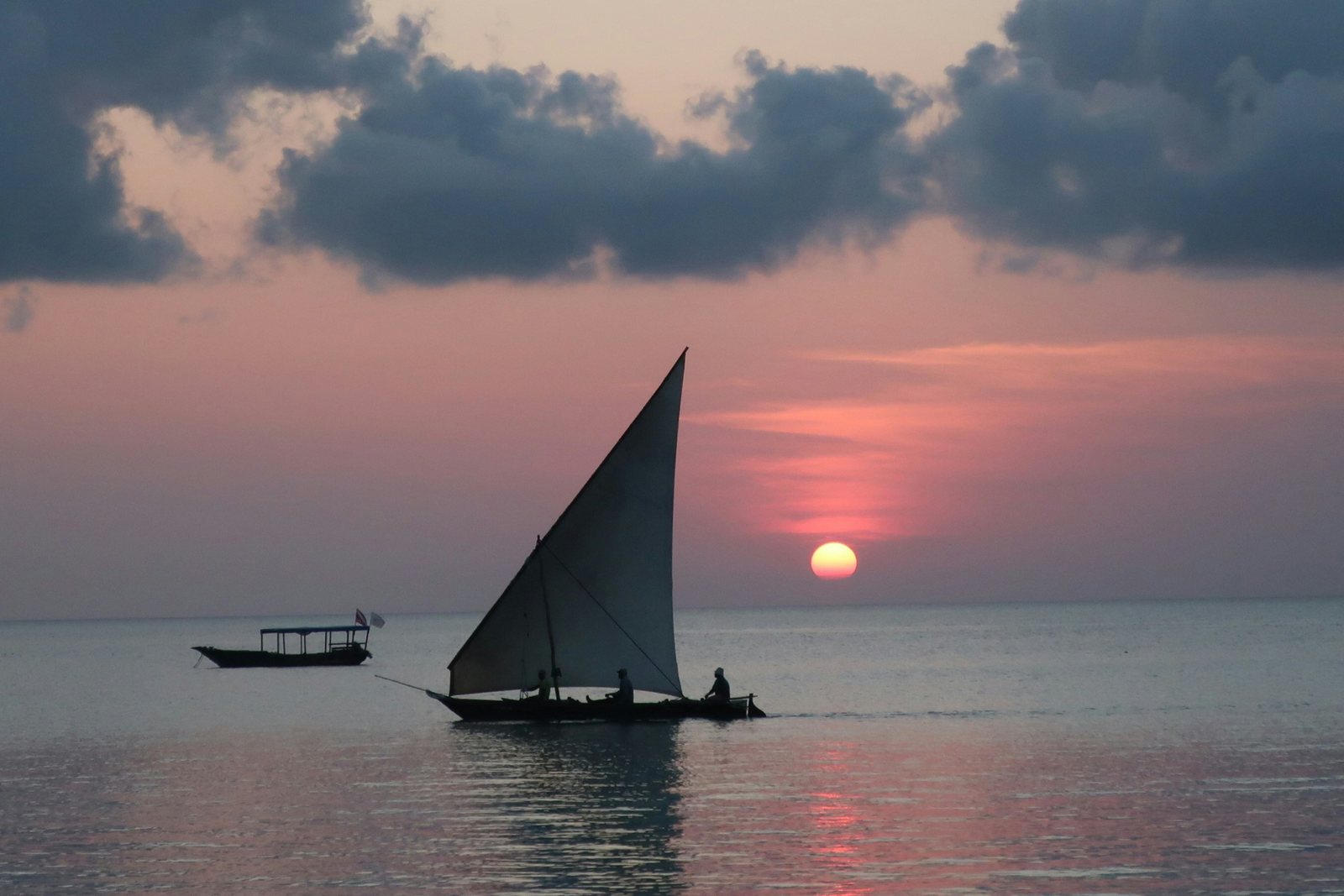A traditional dhow with a triangular sail at sea at sunset, Zanzibar