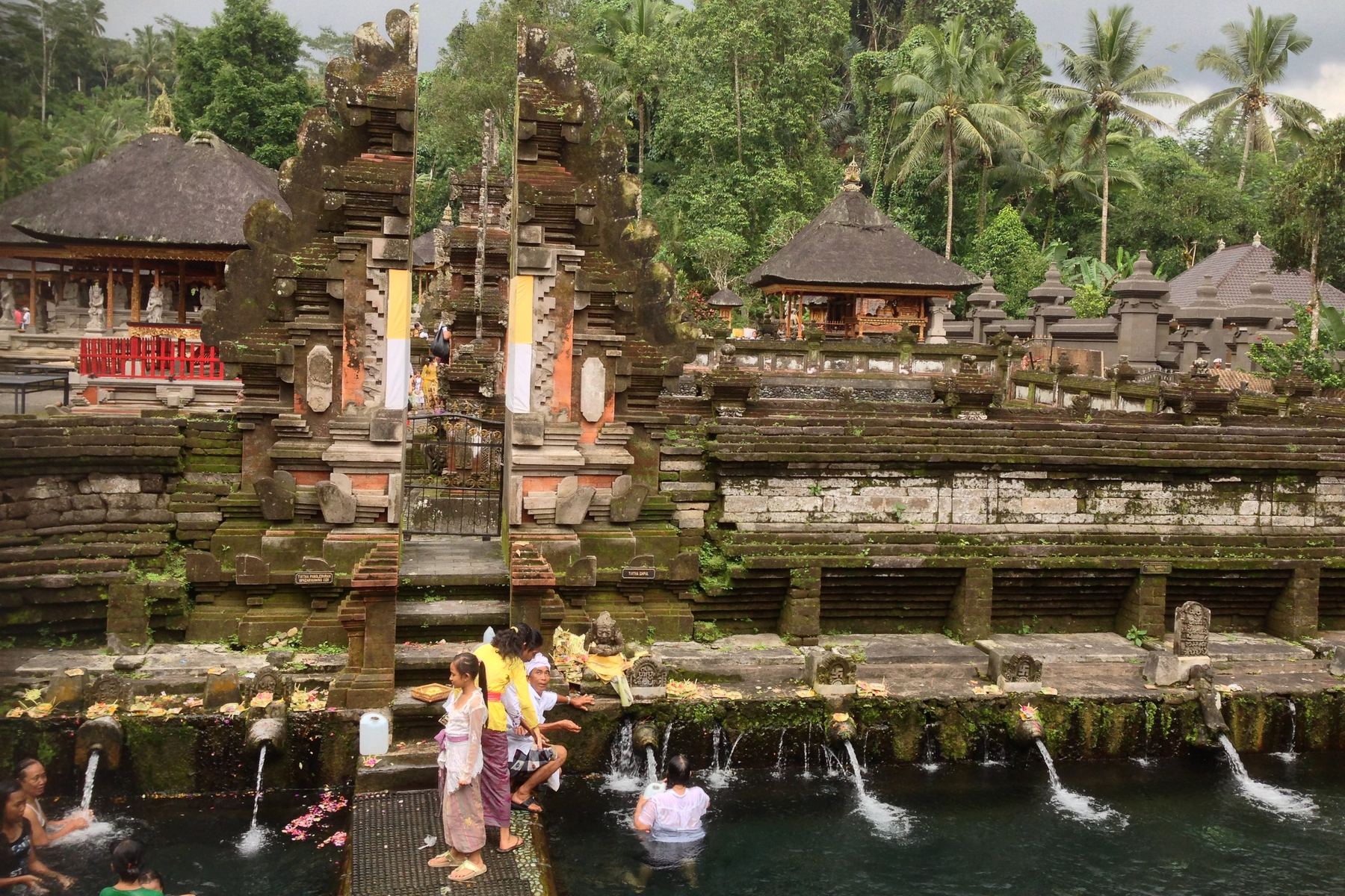 Mensen baden onder de stenen waterspuiten in de heilige baden van Tirta Empul, Bali
